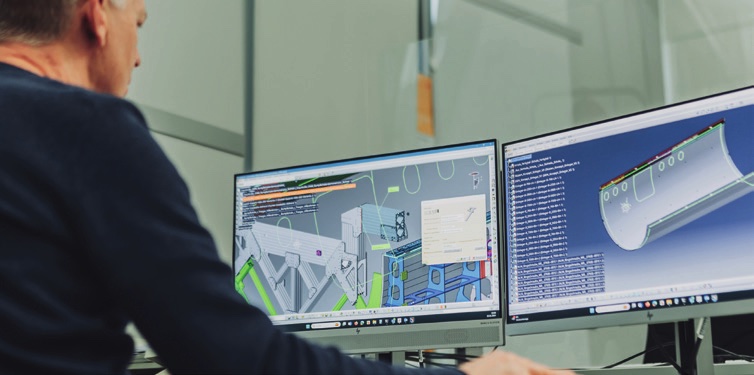 Engineer designing a large-format aerospace tool on two CAD screens
