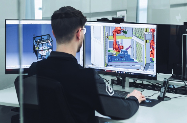 Engineer designing an automated ultrasonic welding cell on CAD screens
